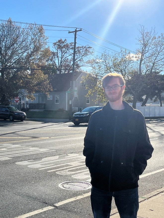The author stands at an intersection of a busy road, underneath of which toxic dry-cleaning chemicals have seeped into the groundwater.